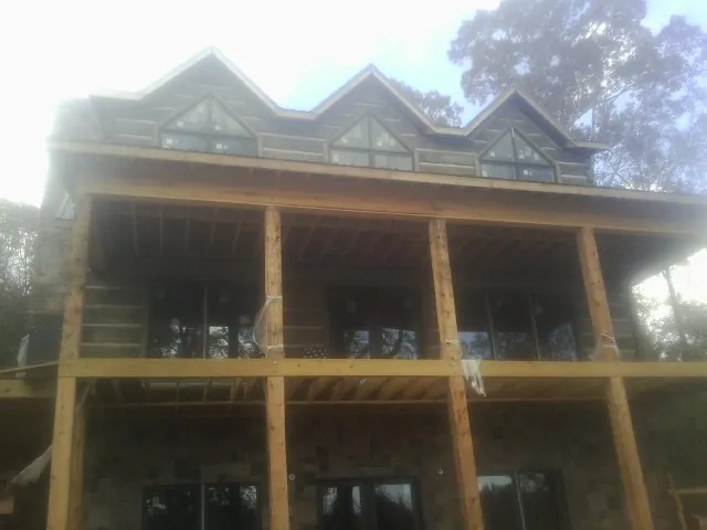 Dormers and porch framing on a large log home under construction — Roof Coating work by our crew in Gary