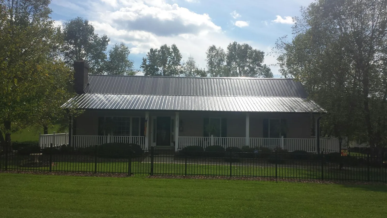 Gray metal roof on a brick ranch with a full width front porch — Gutter Guard Installation work by our crew in Gary